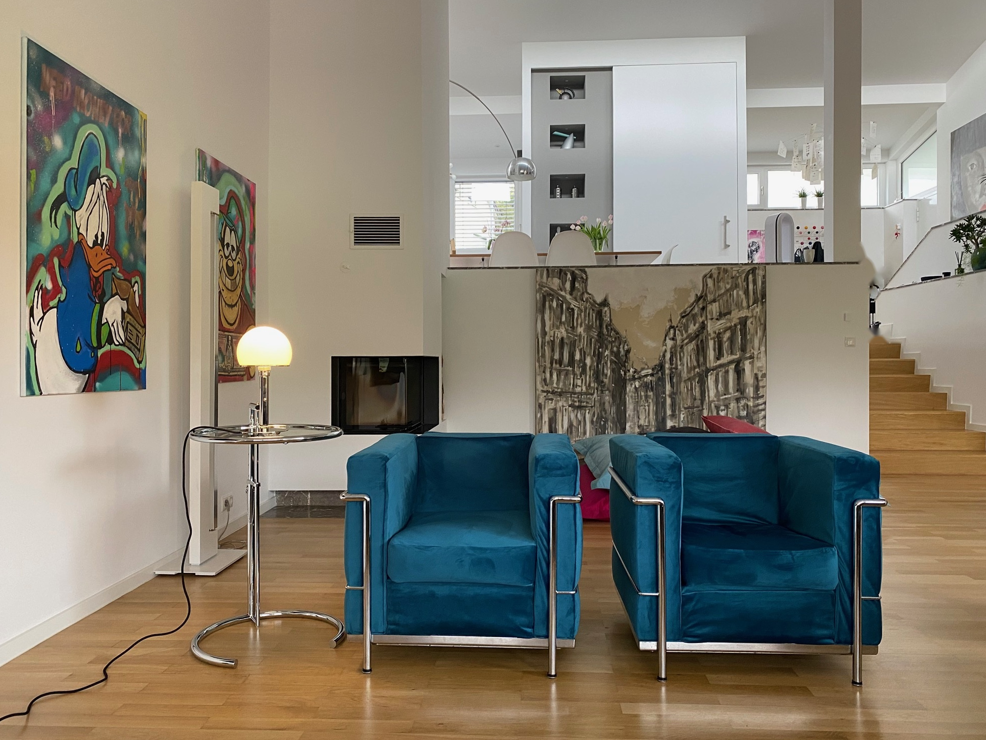 Fertiggestellter offener Wohnbereich mit Kamin, Treppe und blauen Sesseln